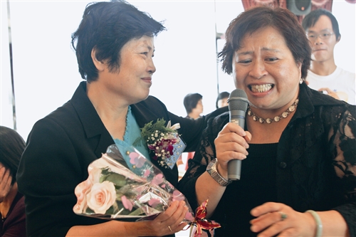 15日舉辦榮退茶會，人二組組長彭梓玲（右）為退休人員獻唱〈掌聲響起〉並獻花，因不捨而哽咽。圖左為退休人員總務處出納組編纂孫扇。（攝影／鄭雅文）