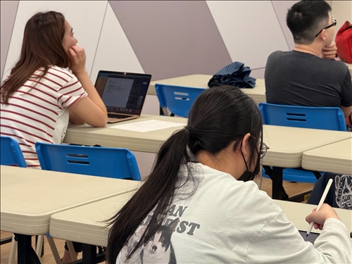 學生一邊使用電腦或平板筆記課程要點，展現高投入程度。