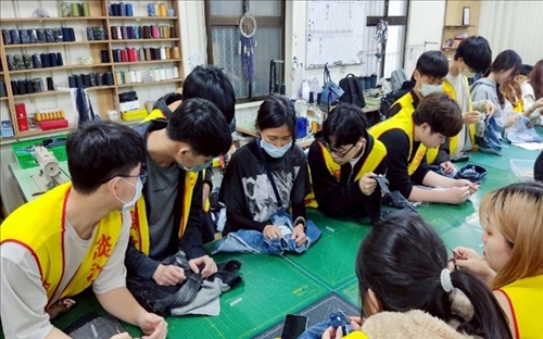 學生向修惜站教師學習如何拆解牛仔褲