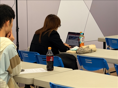 學生利用筆電一邊查閱官方CBAM資料、一邊筆記，展現出高度自主學習與實務操作的積極態度。