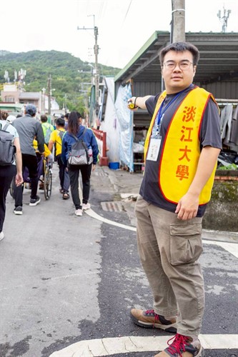 淡江大學志工身穿黃色背心，於健走路線交叉路口負責交通導引，引導參與者安全有序前行。